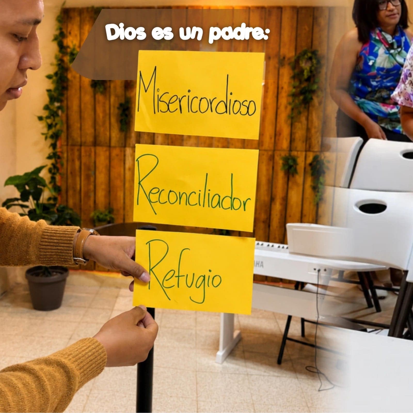 Un joven colocando en la pared las notas «Dios es un padre: misericordioso, reconciliador, refugio»