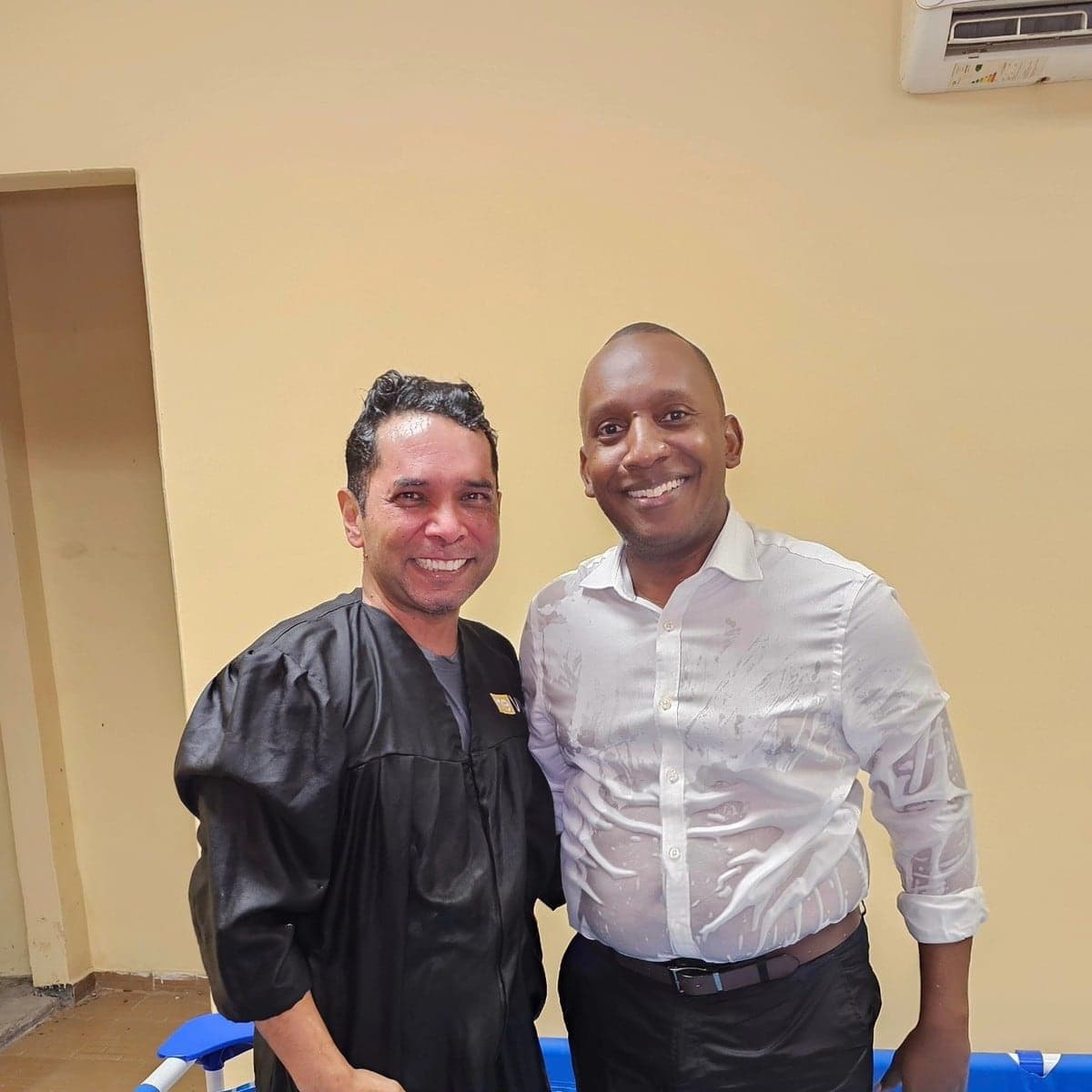 Carlos con el pastor, sonriendo en la piscina el día de su bautismo